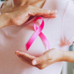 Asian woman show pink ribbon as sign of October Breast Cancer Awareness month